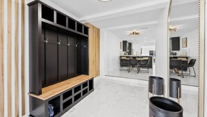 Ein moderner Flur mit einer schwarzen Holzbank, einer Wand mit Spiegeln und einem Essbereich im Hintergrund.