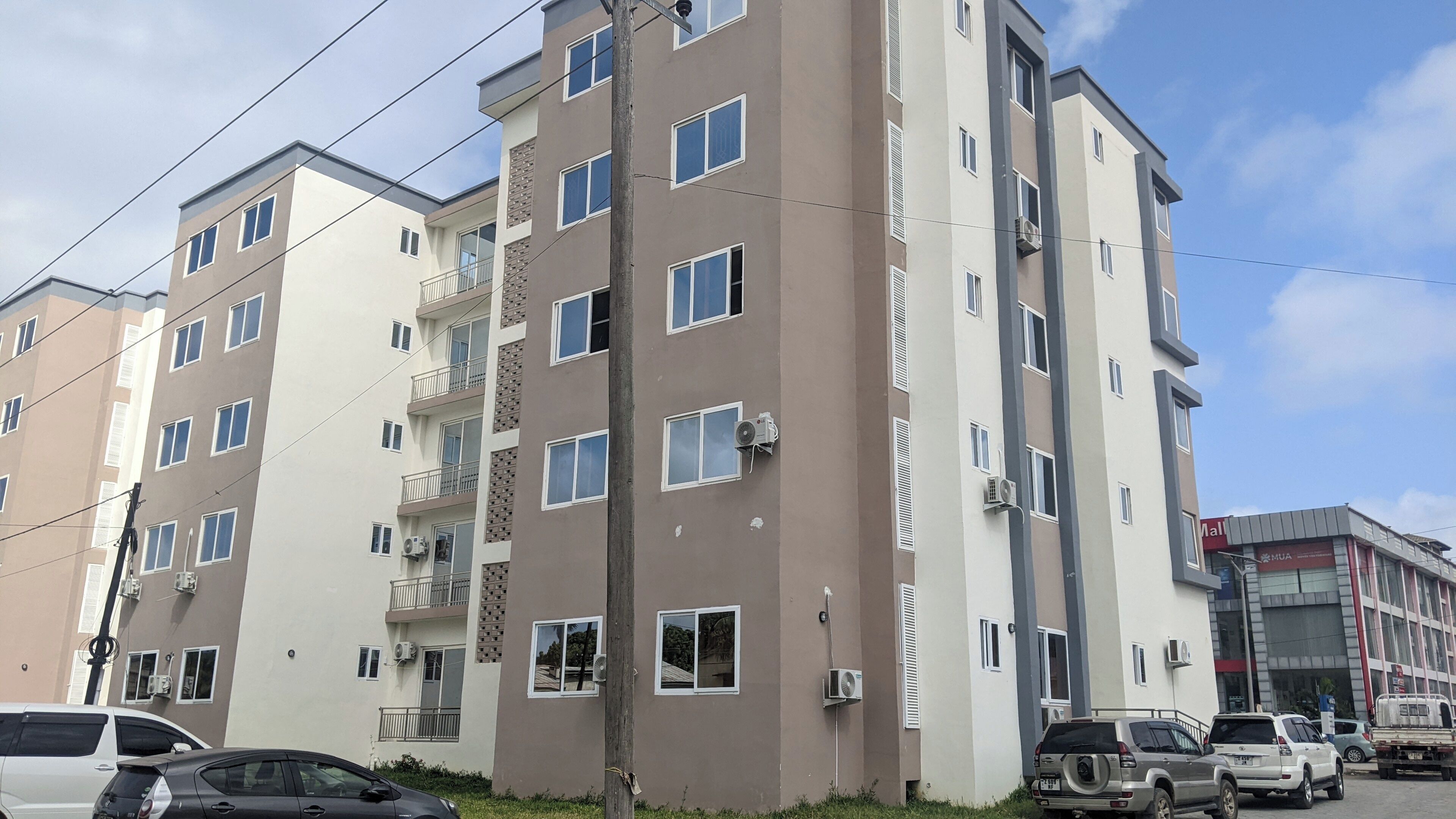 A multi-story residential building with balconies, air conditioning units, and a visible storefront with signage.
