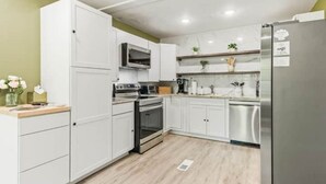 A modern kitchen with white cabinets, stainless steel appliances, and a wooden countertop.