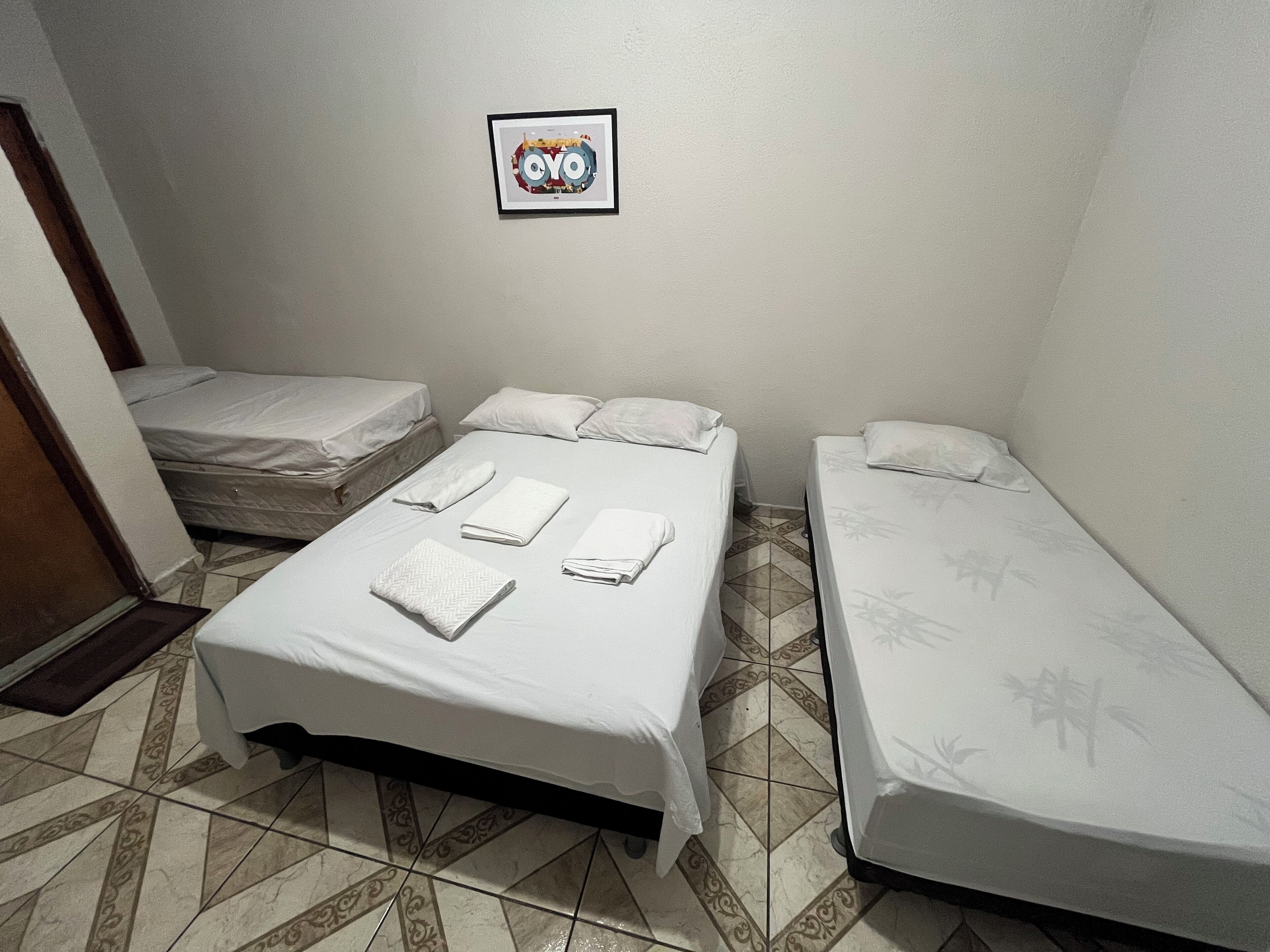Una habitación pequeña y limpia con dos camas individuales, un escritorio pequeño y un cuadro en la pared.