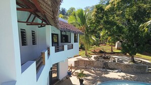 A modern building with a pool, stone pathway, and lush greenery. - SAKATIA ART (Nosy Be)