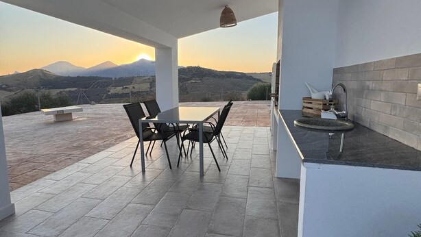 A covered patio with a table and chairs, a sink, and a view of distant mountains. - HOUSE ANA MARIA DISCONNECTION IN THE MOUNTAIN WITH INCREDIBLE VIEWS. PRIVATE SWIMMING POOL. (antequera)