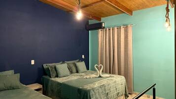 A room with two beds, a wooden ceiling, and a curtain on the window.