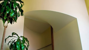 A staircase with a wooden handrail, a potted plant, and a curved wall. - Hotel & Villas HANGAR  (Colon)