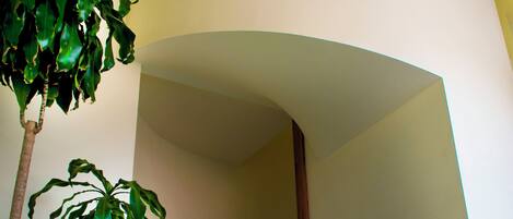 Eine Treppe mit Holzhandlauf, einem Blumentopf und einer gewölbten Wand.