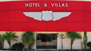 A red building with a sign reading "HOTEL & VILLAS" and a logo with "HANGAR MH". - Hotel & Villas HANGAR  (Colon)