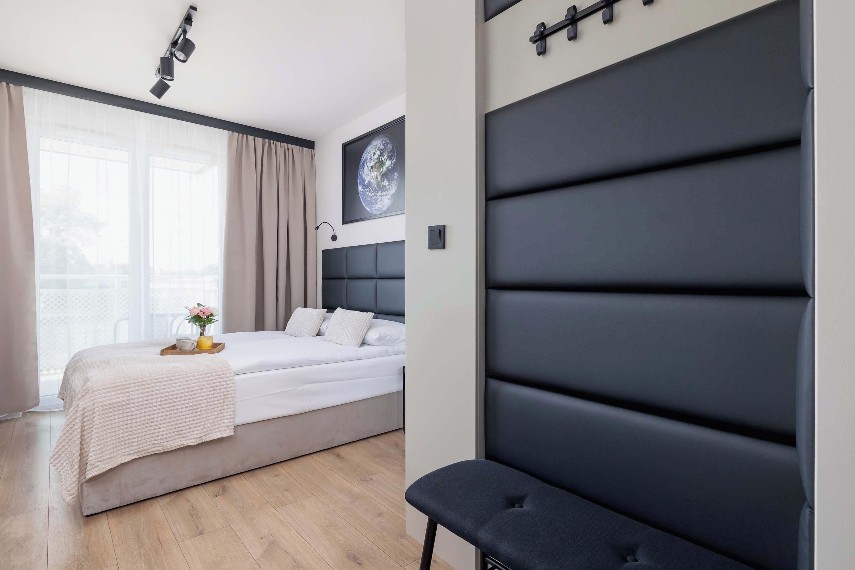 A modern bedroom with a bed, a bench, a window with curtains, and a wall-mounted globe.