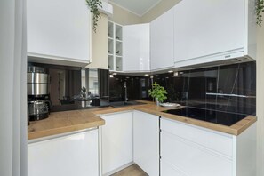 Une cuisine moderne avec des meubles blancs, une plaque de cuisson noire et un plan de travail en bois.