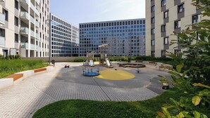 Un patio con un parque infantil, rodeado por edificios modernos con balcones.
