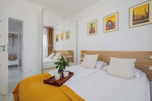 A hotel room with a bed, a mirror, and artwork on the walls.