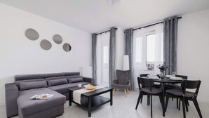 Una sala de estar moderna con un sofá gris, una mesa de centro negra y un comedor con una mesa y sillas.