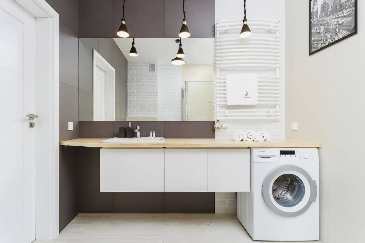 Une salle de bain moderne avec un lavabo, un miroir et un lave-linge.