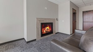 A modern living room with a fireplace, a leather sofa, and a patterned carpet. - Charming 2-bedroom/2 bath apartment with spa & fitness room amenities in Mankato (Mankato)