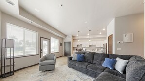 A spacious living area with a grey sofa, a grey armchair, and a patterned rug. - Charming 2-bedroom/2 bath apartment with spa & fitness room amenities in Mankato (Mankato)