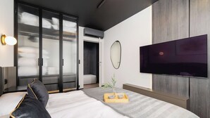 Una habitación de hotel moderna con una cama grande, un televisor de pantalla plana montado en la pared y un ventanal corredero que da a un balcón.