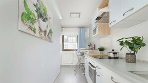 A modern kitchen with white cabinets, a stainless steel oven, and a countertop with a potted plant. - Spacious Apartment | 3 Bedrooms | Parking and Balcony (Kraków)