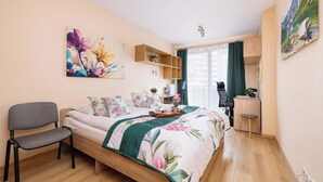 Ein Schlafzimmer mit einem Bett, einem Sessel, einem Schreibtisch und einem Regal.