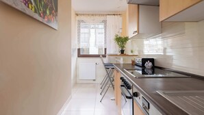 Eine moderne Küche mit Edelstahlgeräten, einer weißen Fliesenspiegel und einem Fenster mit Spitzenvorhängen.