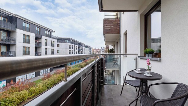 Ein Balkon mit Blick auf eine Stadtlandschaft, ein Tisch mit Stühlen und ein Blumentopf.