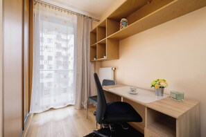 Une chambre moderne équipée d’un bureau, d’une chaise et offrant une vue par une fenêtre agrémentée d’un rideau.