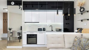 A modern kitchen with white cabinets, a built-in oven, and a dining area with a table and chairs.