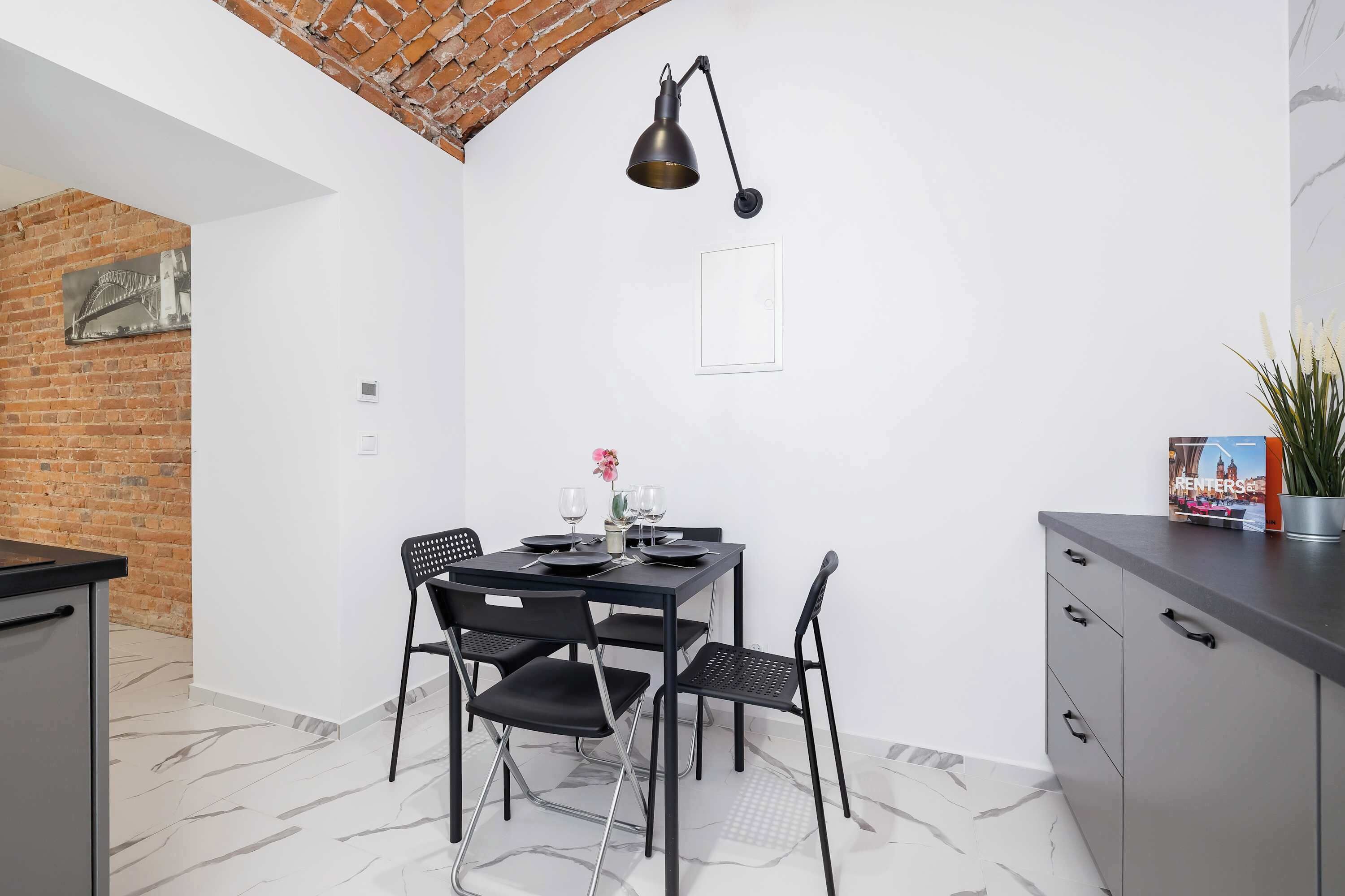 A compact dining area with a table, chairs, and a pendant light.