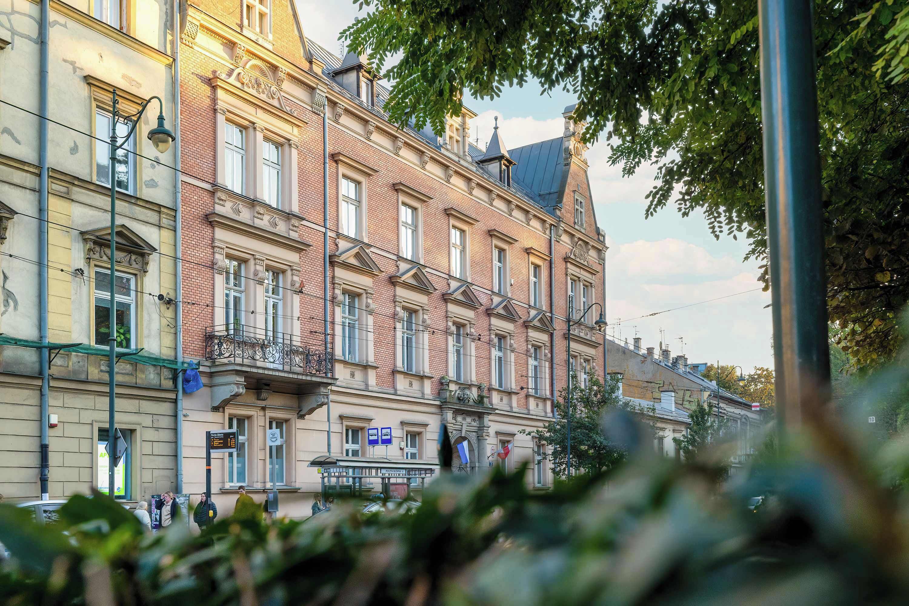 En byggnad med flera våningar i en klassisk arkitektonisk stil, med en balkong och en skylt.
