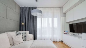 A modern bedroom with a large bed, a TV, and a window with curtains.