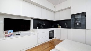 A modern kitchen with white cabinetry, a black countertop, and a Bosch range hood.