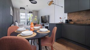 A modern dining area with a round table, orange chairs, and a black ceiling.