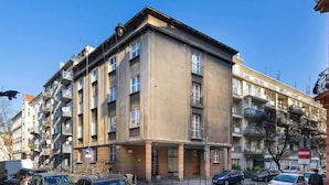 A multi-story building with balconies, a ground-level entrance, and a clear sky. - Bright Apartment in Krakow | Close to Market Square, Place to Work (Kraków)