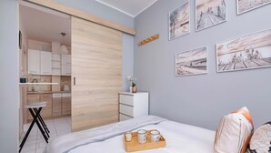 Un dormitorio moderno con cama, una mesita de noche, una bandeja con tazas y vistas a la cocina y al baño.
