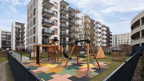 Un parque infantil con columpios y estructuras para escalar, rodeado de edificios de apartamentos.