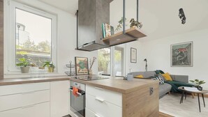 A modern kitchen with a built-in oven, a wooden island, and a window overlooking a garden.