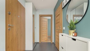 A hallway with wooden doors, a white cabinet with a mirror, and a potted plant.