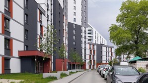 A modern apartment building with a mix of white and grey facades, red accents, and balconies. - Elegant Apartment with Balcony | Parking | Workspace (Kraków)