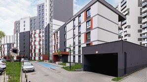 A modern apartment building with multiple floors, a parking area, and a swimming pool.