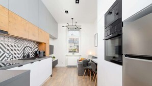 Cocina moderna con una isla central, electrodomésticos integrados y un comedor con sofá y sillas grises.