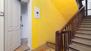 Una escalera con barandilla de madera y pared amarilla.