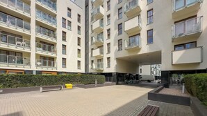 En flervåningsbyggnad med bostäder, balkonger, en stenlagd innergård och ett område för cykelparkering.