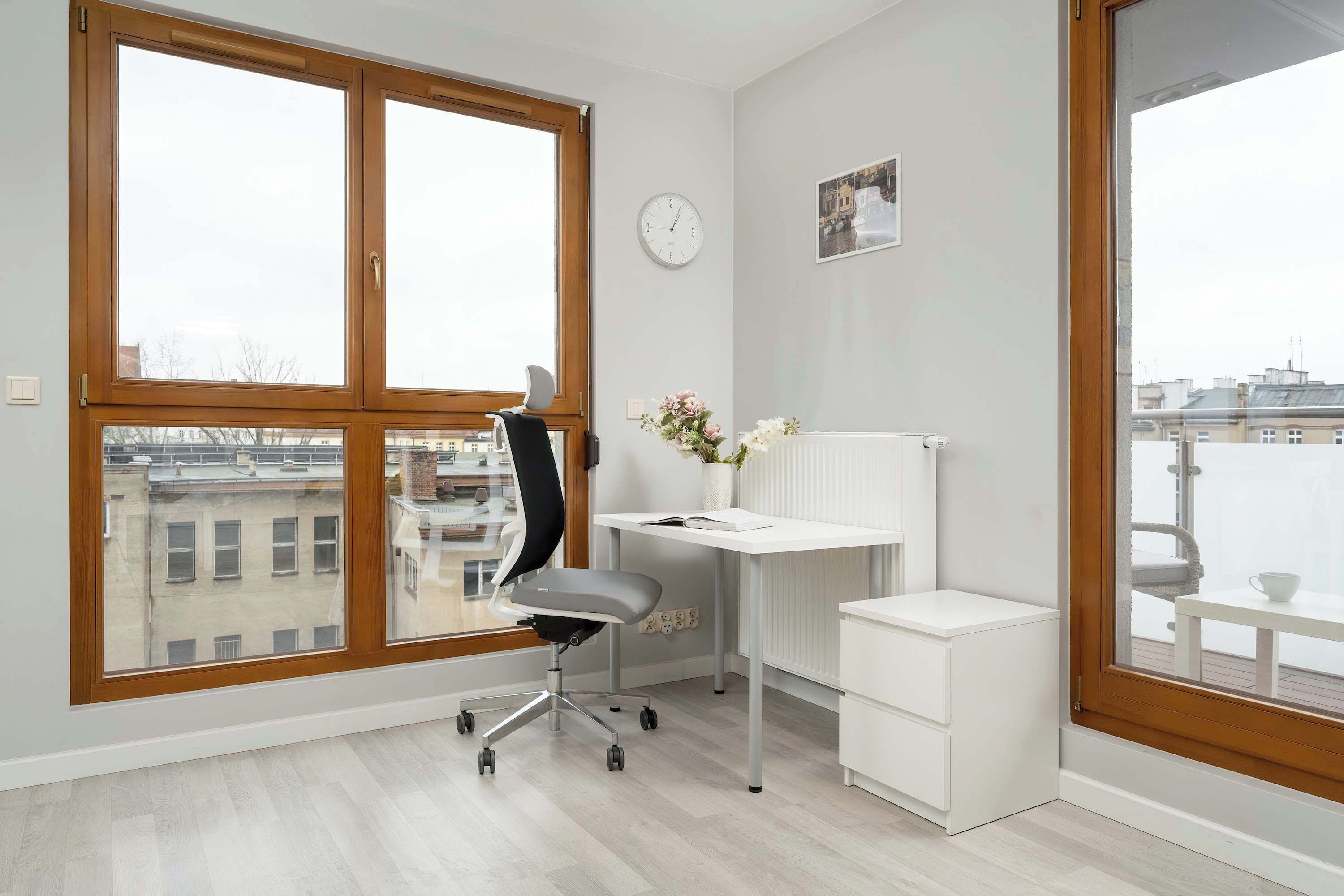 Un espacio de oficina moderno con un ventanal grande, un escritorio, una silla y un radiador.