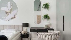 Un dormitorio con cama, mesita de noche, lámpara, silla, escritorio, espejo y decoración en la pared.