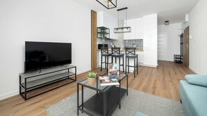 Ein modernes Wohnzimmer mit einem Flachbildfernseher, einem Couchtisch mit Zeitschriften und einem blauen Sofa.