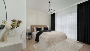 Ein modernes Schlafzimmer mit einem Bett, Nachttischen, einem klaren Stuhl, einer dekorativen Vase und einem großen Fenster mit leichtem Vorhang.
