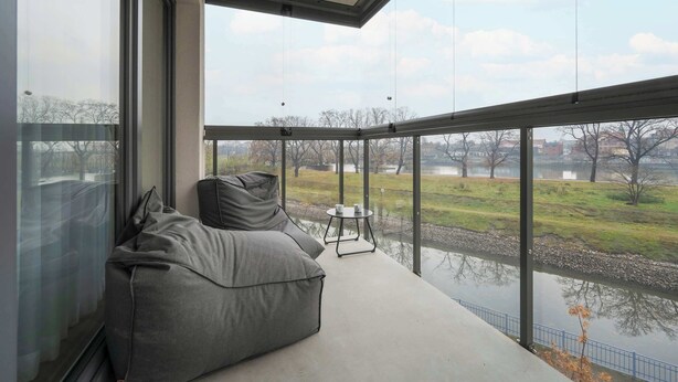 Ein modernes Zimmer mit einem großen Fenster, einem grauen Sofa und einem kleinen Tisch mit Tassen.