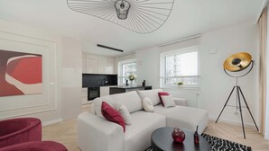 Ein modernes Wohnzimmer mit einem weißen Sofa, roten und weißen Kissen, einem schwarzen Couchtisch und einer Stehlampe.