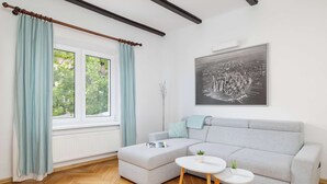 Una sala de estar moderna con un sofá seccional gris, una mesa de centro blanca y una ventana con cortinas azul claro.