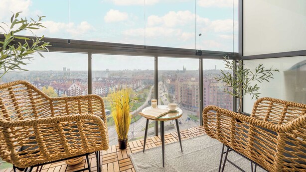 A balcony with wicker chairs, a small table, and potted plants.