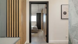 Un pasillo con un separador de listones de madera, una cama a lo lejos y una obra de arte enmarcada en la pared.