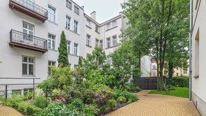A courtyard with a paved walkway, surrounded by multi-story buildings with balconies and windows.